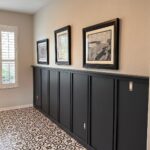 Dark grey board and batten paneling on a wall above patterned tile flooring.