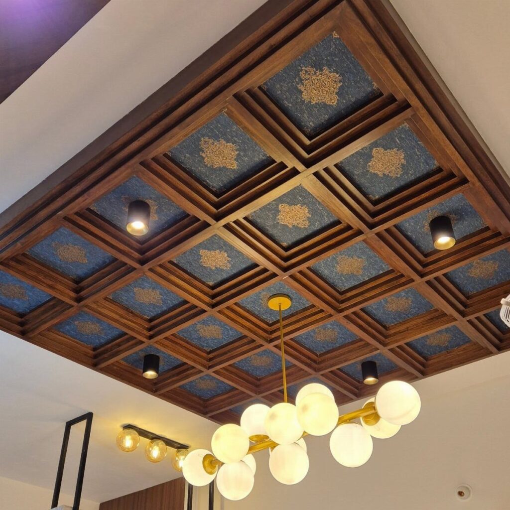 Coffered wooden ceiling with blue patterned panels and a modern white globe chandelier.