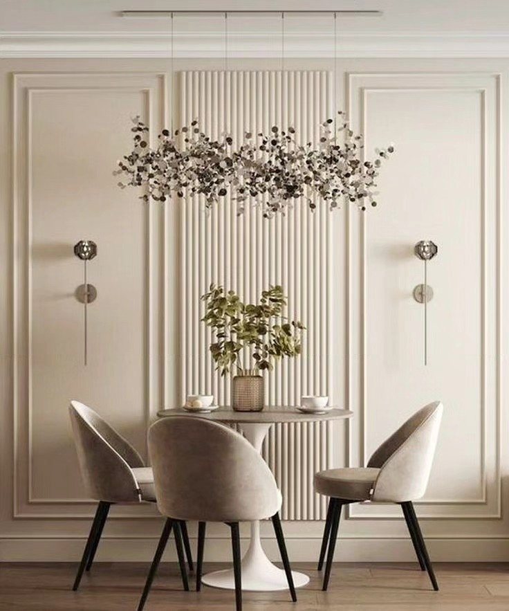 Fluted wall paneling behind a dining table with chairs and a branch-like chandelier.