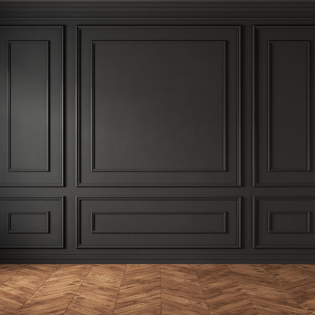 Dark grey wall with decorative rectangular molding panels above a herringbone wood floor.
