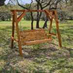 Wooden garden bench swing hanging from a matching A-frame structure on a grassy lawn