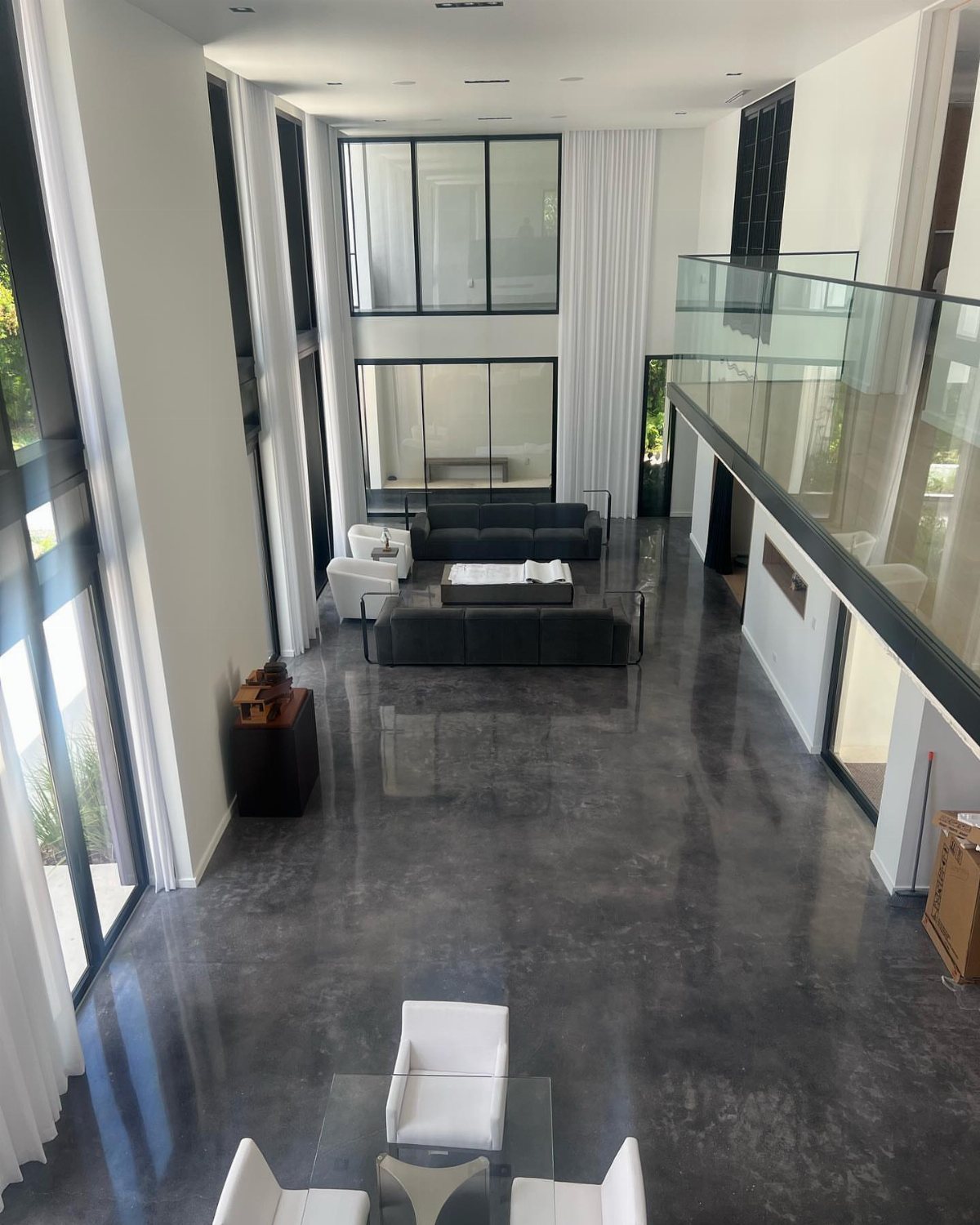 Polished dark grey concrete flooring in a large, modern living room with high ceilings.