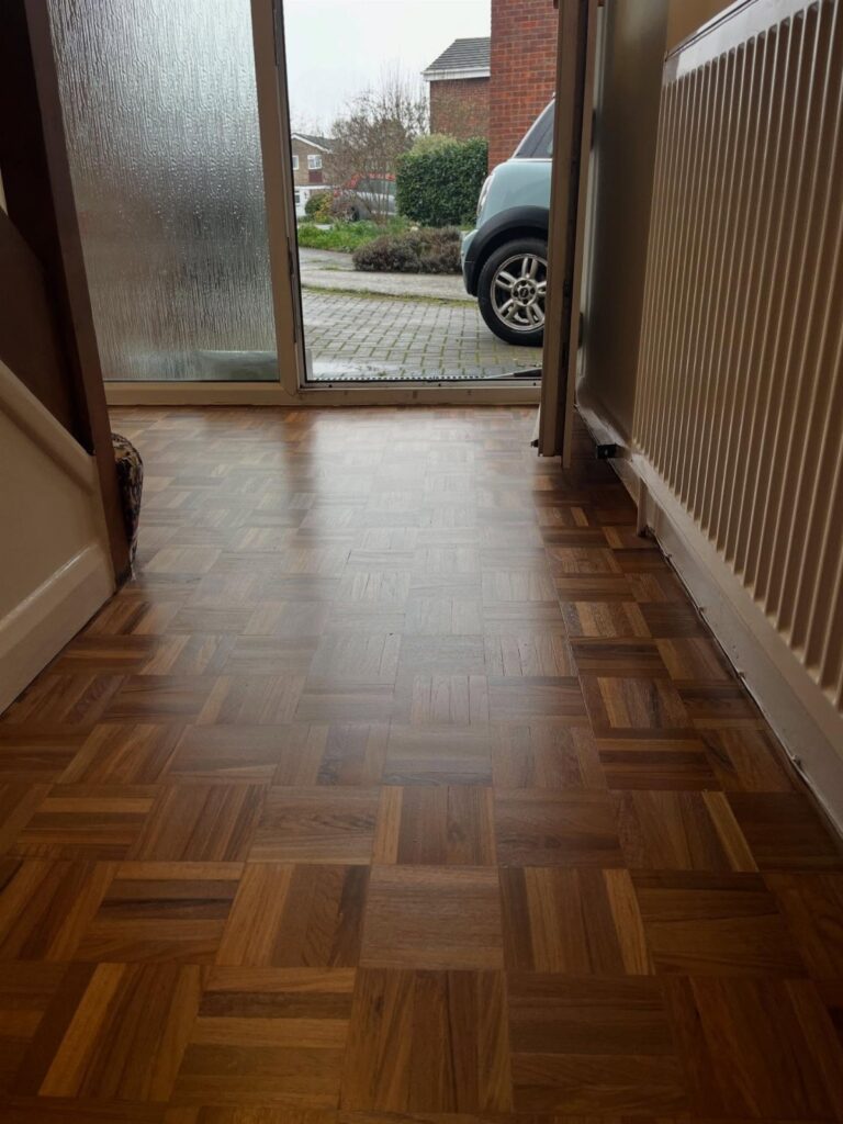 Wooden parquet floor with a mosaic pattern of small square blocks in a hallway.