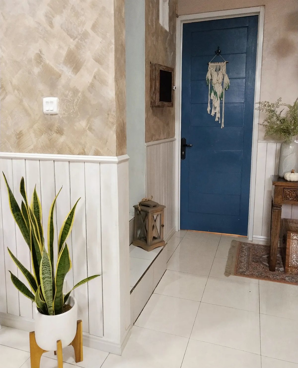 White vertical wainscoting on the lower half of a hallway wall near a blue door.